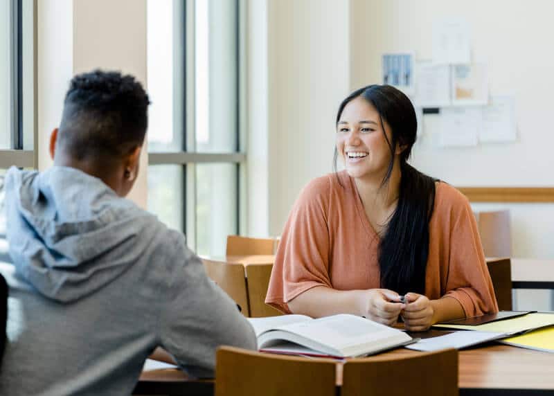 Photo of two young people seated and having a discussion