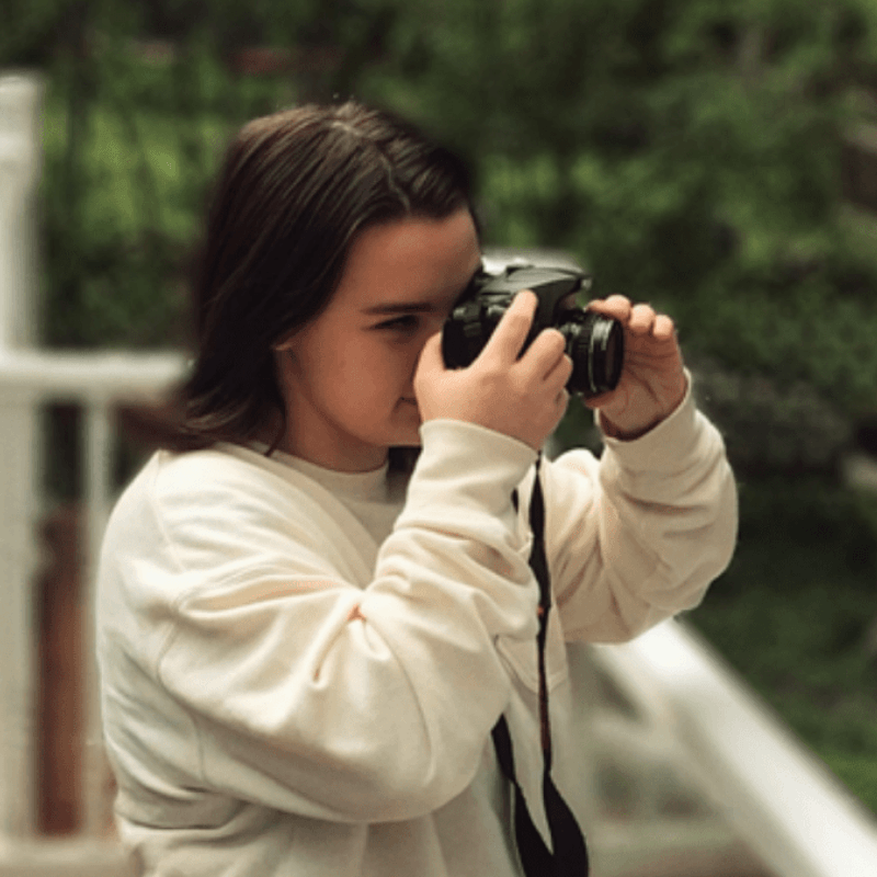 Young girl focuses film camera that was gifted by Treehouse.